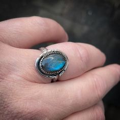 A handmade ring with a beautiful blue shiny labradorite. This ring has a unique look with the serrated setting and is made of sterling silver. The band has an engraved pattern. The ring has a width of 4 mm, a thickness of 1.5 mm and is beautiful for every day. The labradorite stone is 14mm x 10mm. Available in size 9. Also take a look at my other sterling silver rings: https://www.etsy.com/nl/shop/IngeJewels?ref=seller-platform-mcnav&section_id=13764110 Adjustable Cabochon Labradorite Ring, Adjustable Labradorite Cabochon Ring, Hand Forged Labradorite Blue Jewelry, Hand Forged Blue Labradorite Jewelry, Blue Labradorite Ring, Unique Blue Labradorite Ring, Bohemian Blue Labradorite Rings, Silver Labradorite Hand Forged Rings, Hand Forged Silver Labradorite Rings