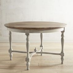 an oval table with two legs and a wooden top on a hard wood floor in front of a white wall