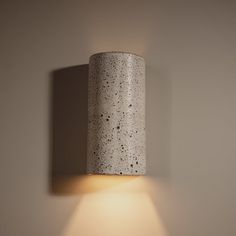 a light that is on the wall next to a white lamp shade with black speckles