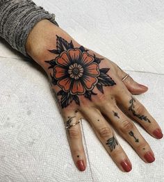 a woman's hand with an orange flower tattoo on it