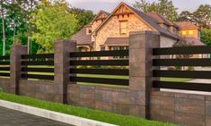 a house behind a fence with grass and trees in the background