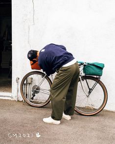 a man bending over with his bike leaning against the wall