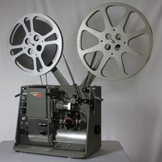 an old fashioned movie projector with two reels on it's sides and a camera attached to the side