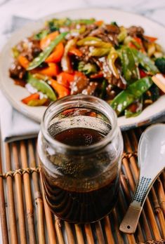 a glass jar filled with food sitting on top of a bamboo mat next to a spoon