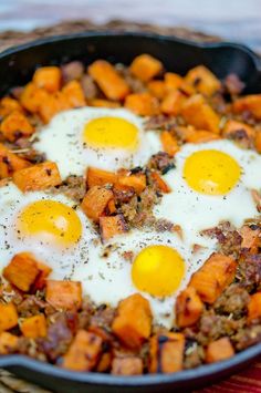 two fried eggs on top of sweet potatoes in a skillet