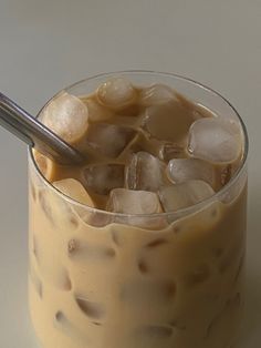 an iced drink in a glass with ice cubes and a spoon on the side