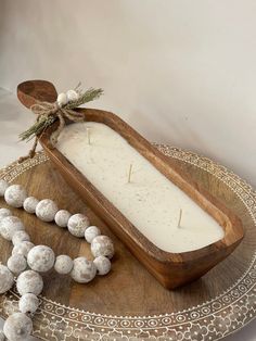 a wooden tray holding a candle and some white balls