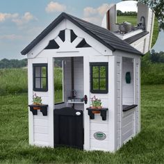 a small white and black play house with potted plants