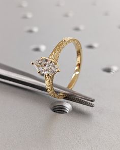 a diamond ring sitting on top of a piece of metal next to a pair of scissors