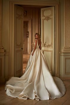 a woman in a wedding dress is standing by an open door with her back turned to the camera