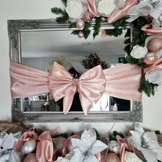 a mirror with pink and white bows on it next to christmas decorations in front of a silver framed mirror