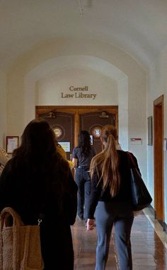 two women are walking down the hallway in front of an entrance to a law library