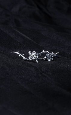 two silver roses sitting on top of a black cloth