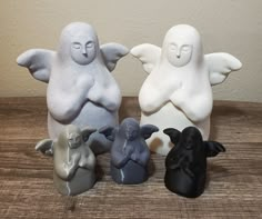 four small ceramic figurines sitting on top of a wooden table