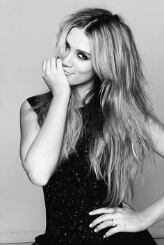 black and white photograph of a woman with long blonde hair posing for the camera, her hand on her face