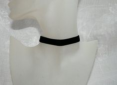 a white mannequin head wearing a black choker