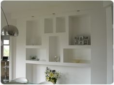 a dining room table with chairs and shelves on the wall