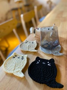 three crocheted cats sitting on top of a wooden table