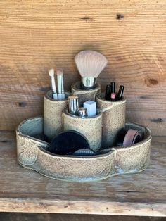 a wooden table with a cup holder filled with makeup and brushes