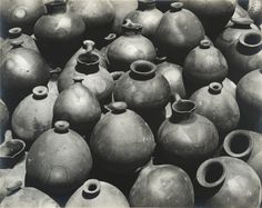 black and white photograph of many vases stacked on top of each other in rows