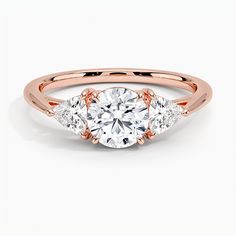 a rose gold engagement ring with three stones on the band and an oval center stone