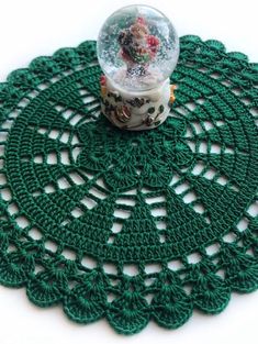 a snow globe sitting on top of a doily covered in green crochet