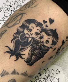 a couple of tattoos on the legs of someone's leg, one is kissing