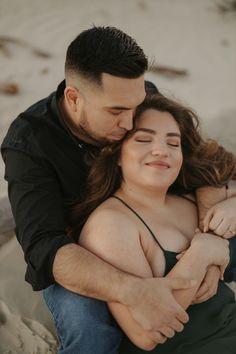 a man and woman hugging each other on the beach