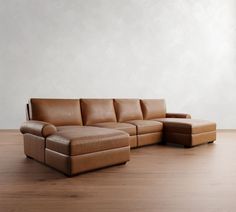 a brown leather couch sitting on top of a hard wood floor next to a white wall