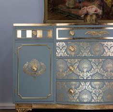 a blue and gold painted dresser with ornate designs