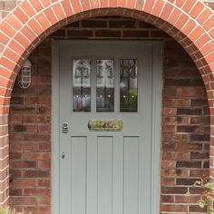 a grey door with three glass panes on the top and bottom, in front of a brick wall