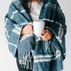 a woman holding a coffee cup wrapped in a blanket