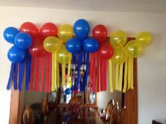 balloons and streamers are hanging from the ceiling above a dining room table in front of a mirror