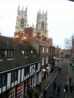 people are walking down the street in front of some old buildings with towers on top