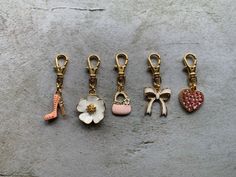 five different types of keychains with charms attached to them on a stone surface