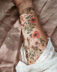 a woman's arm with flowers on it and a lace around the wrist is shown