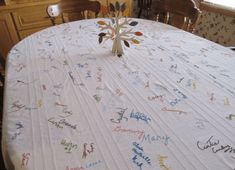 a white table with many names on it and a tree in the center surrounded by chairs