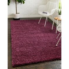 a purple rug in a room with white chairs and a potted plant on the floor