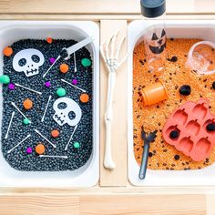 two trays filled with halloween themed food and plastic utensils sitting on top of a wooden table