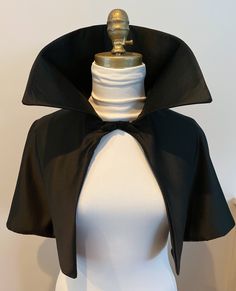 Gothic Victorian Renaissance Vampire Cape in Black Satin.  Made of the Finest Bridal Satin and fully lined.  This cape or shrug  is a full thirteen inches long with a very large vampire collar.  Another length is 24 inches and a full 30 inch cape is also available on the pull-down menu.  A great  accessory to wear over any top or dress or alone or with a corset.  Closure is made of a weaved satin and holds the cape closed at the neckline.   Great gift for yourself or your mistress.  This cape is made in a universal size, but you can email me if you prefer it slightly larger at the shoulders.  It can be made in other satin colors, just e-mail me for color choices. Cape With Collar, Fitted Vampire Outerwear For Halloween, Vampire Collar, Cape Collar, Fitted Gothic Cape For Costume, Vampire Style Fitted Costume Outerwear, Fitted Costume Accessories For Halloween Evening, Gothic Cape For Costume Party In Fall, Black Gothic Cape For Costume Party