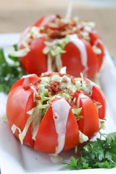 two tomatoes with lettuce and bacon on them are sitting on a white plate