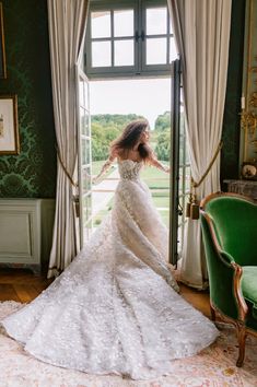 a woman standing in front of a doorway wearing a wedding dress and holding her arms out