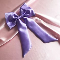 a purple satin bow laying on top of a bed