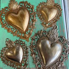 four metal heart shaped plaques on a green door with ornate designs and filigrees