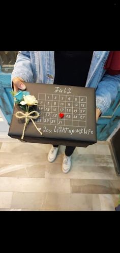 a person holding a box with a flower in it and a calendar on the side