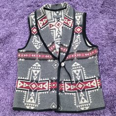 a vest that is sitting on top of a purple carpet with an arrow design on it