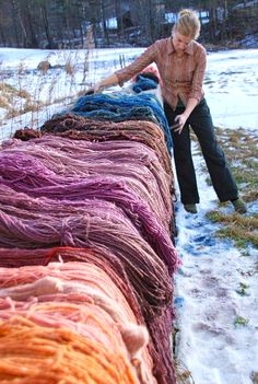 a woman standing next to a large pile of yarn in the middle of snow covered ground