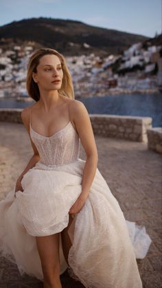 a woman in a white dress is sitting on a ledge