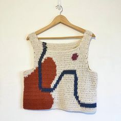 a crocheted top hanging on a wooden hanger