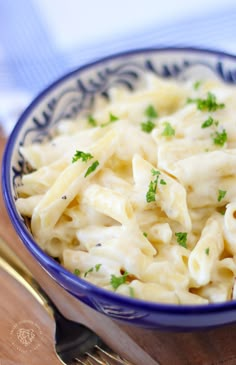 a blue bowl filled with macaroni and cheese on top of a wooden cutting board